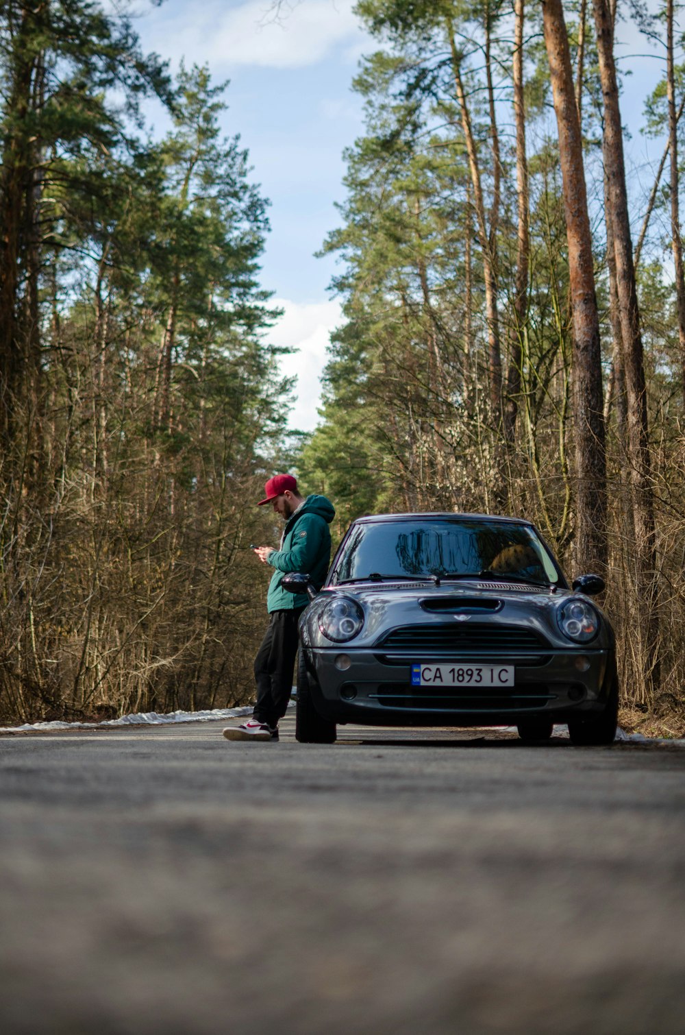 hombre en chaqueta roja de pie junto a un coche negro