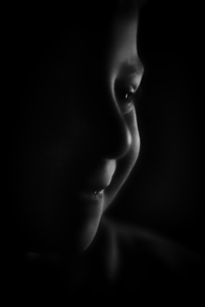 A close-up of a child's face illuminated by gentle light, showing a hopeful smile