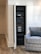A neatly organized server rack is positioned within a recessed area of a room. The rack holds various electronic equipment, including amplifiers, switches, and other audio-visual components. The room features a wooden floor and white paneled walls. A gray upholstered armchair is placed nearby, adding a homey touch to the setting.