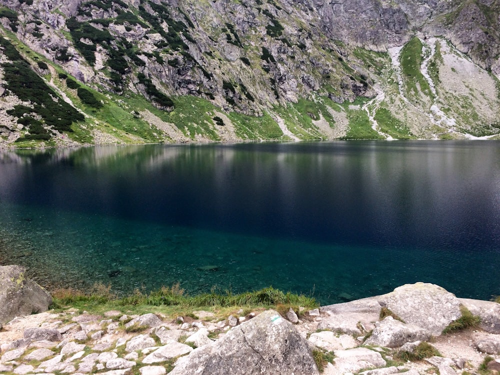 green lake near mountain during daytime