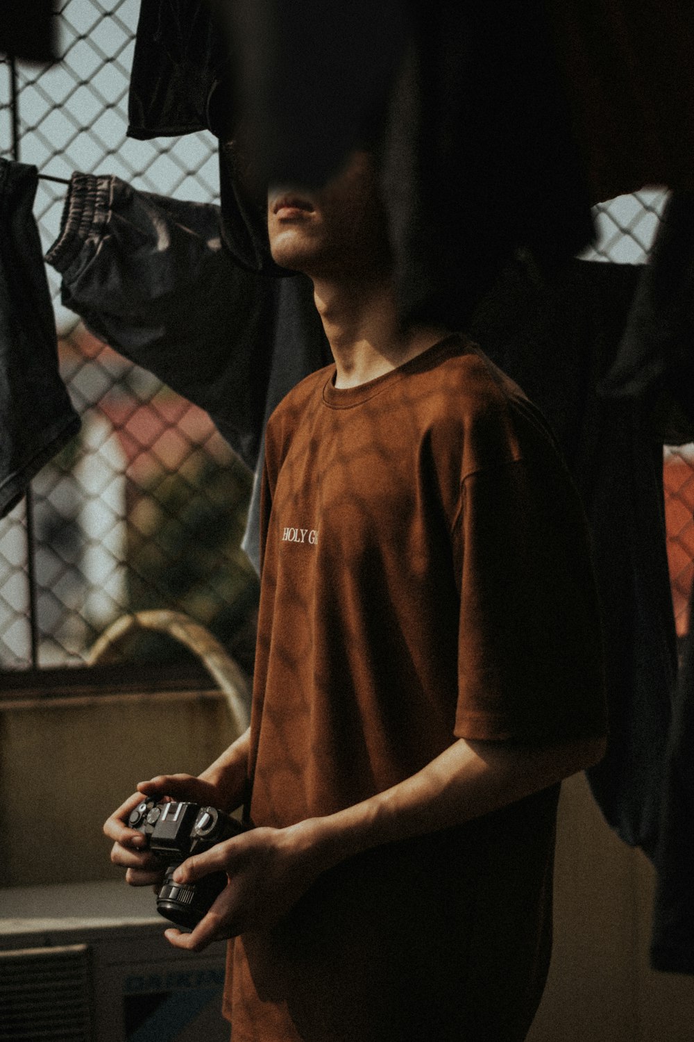 man in brown v neck shirt holding black smartphone