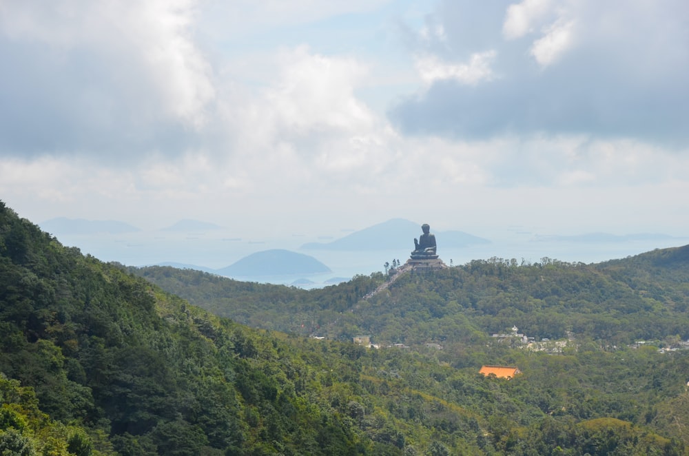 Grüne Bäume auf dem Berg tagsüber unter weißen Wolken