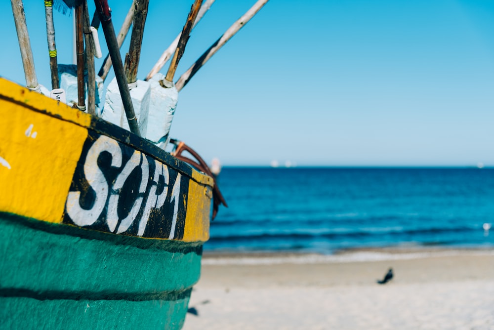 blue and yellow wooden boat on beach during daytime