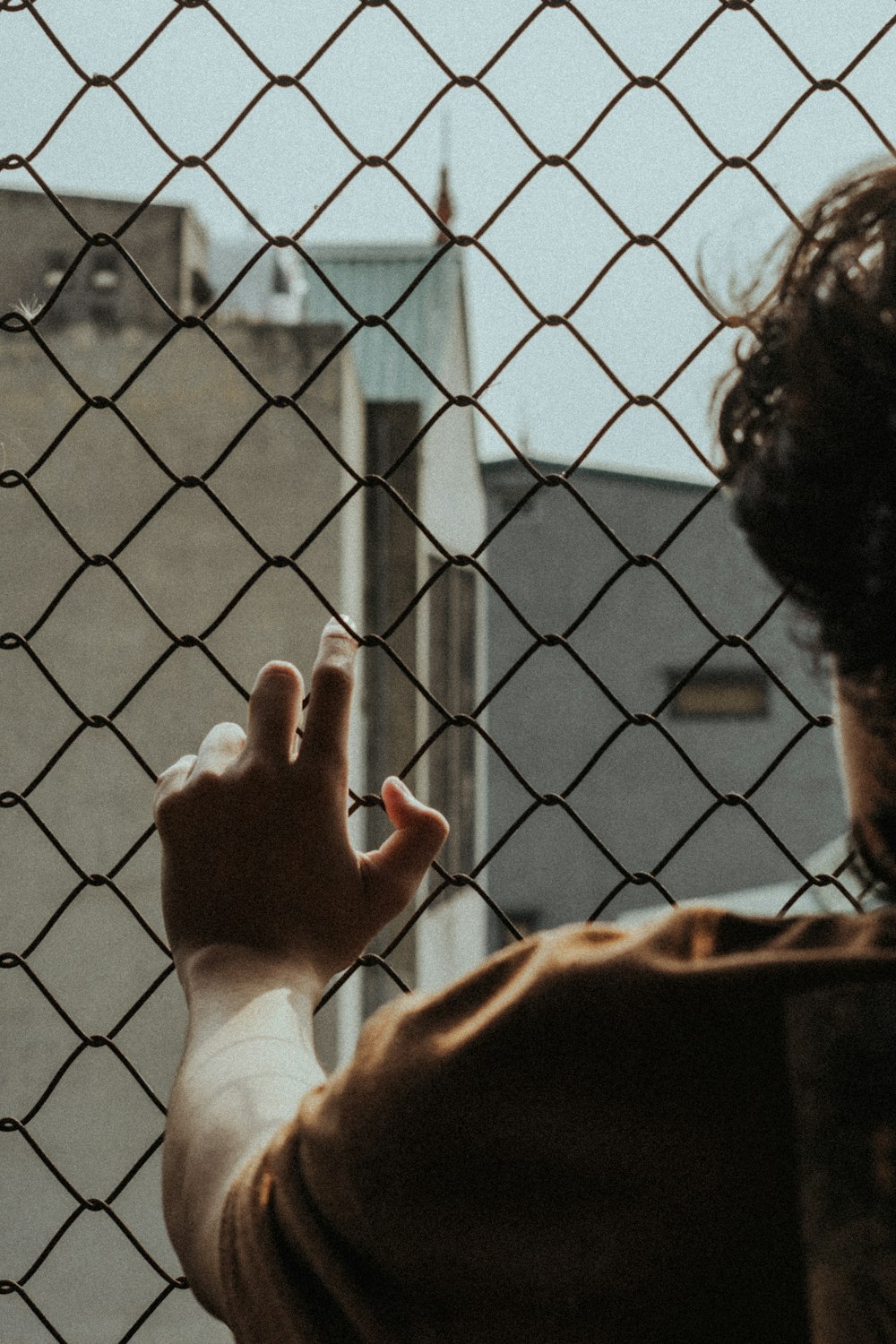 person in white long sleeve shirt holding on gray metal fence