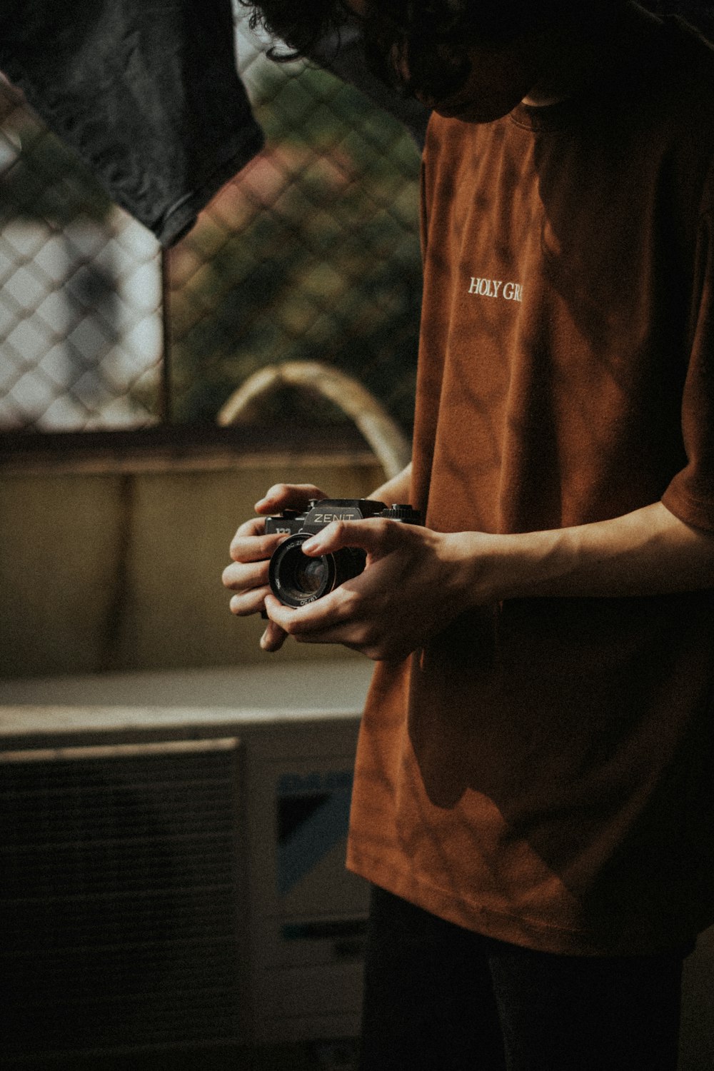 man in brown crew neck t-shirt holding black and silver camera