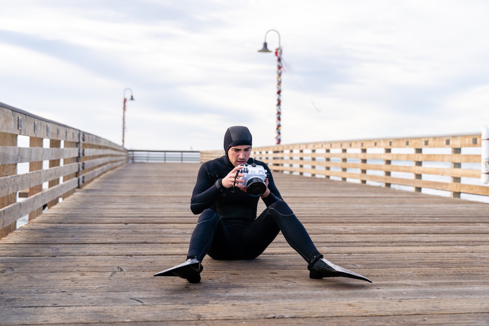 man in black jacket and black pants sitting on brown wooden floor