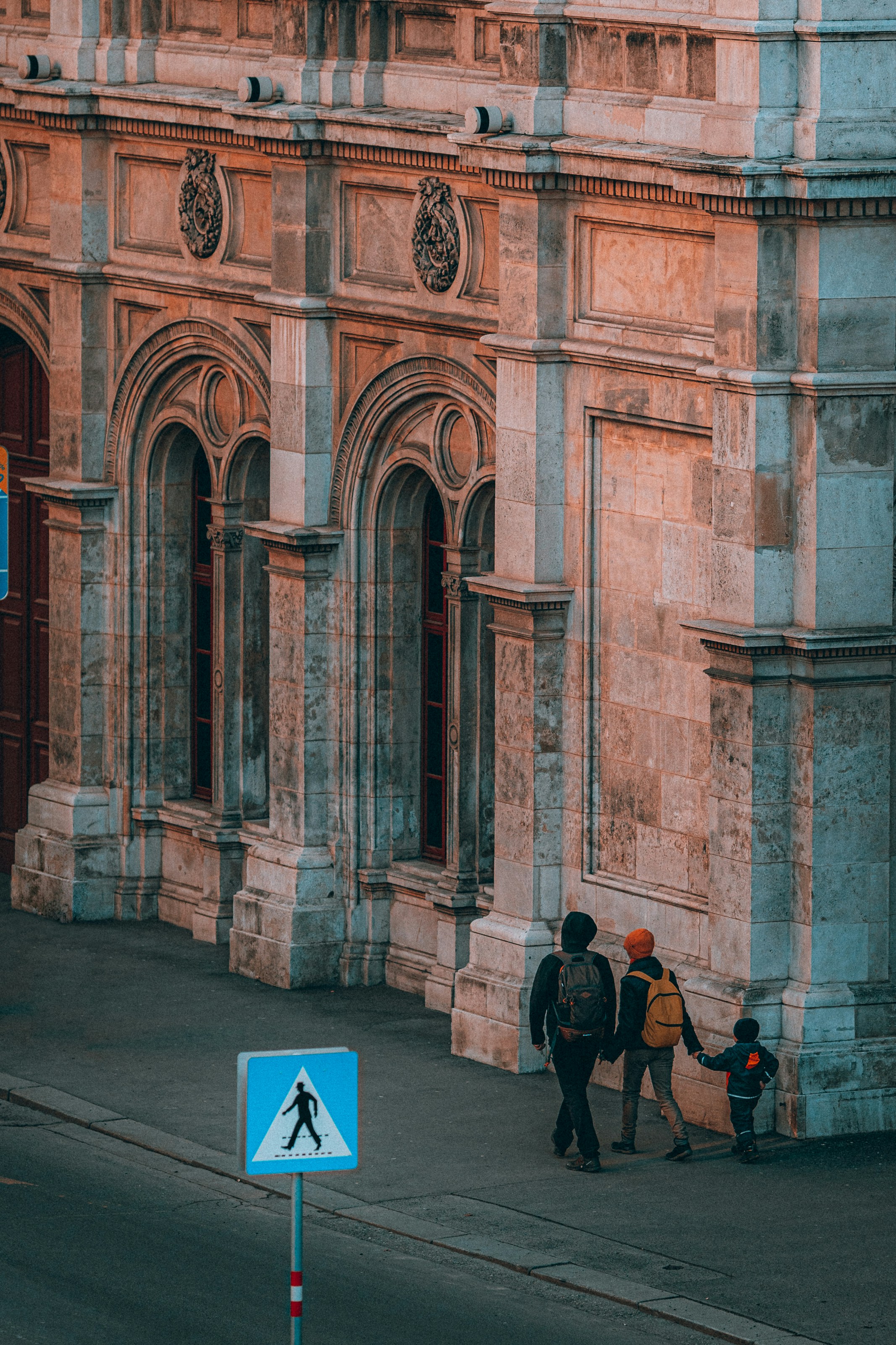 Mann in schwarzer Jacke und schwarzer Hose sitzt auf brauner Holzbank