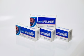 Several boxes of Areplivir medication are displayed on a clean white surface. Each box features prominent blue and white colors with text in a foreign language. The design includes an image resembling a microscopic view of a virus.