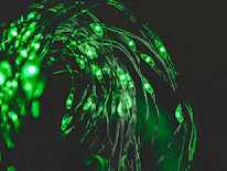 Close-up of a modular LED flow arts kit glowing bright blue and green against a dark background.