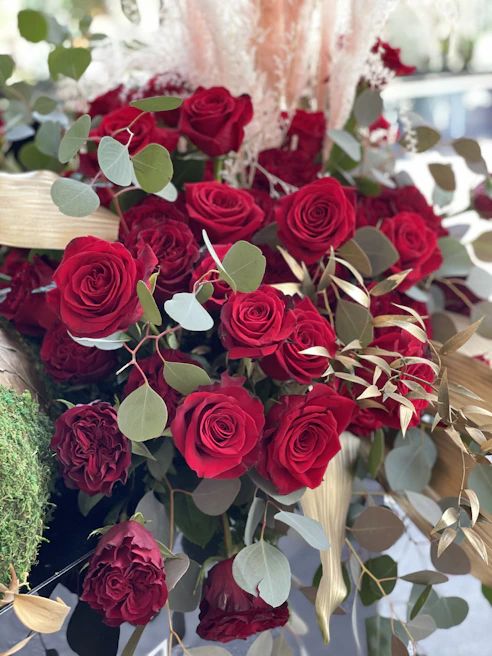 An elegant centerpiece featuring deep red roses and eucalyptus leaves, perfect for a romantic dinner.