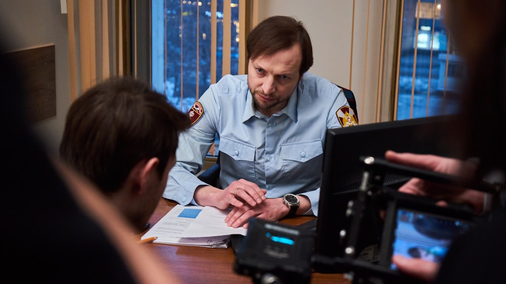 man in blue button up shirt sitting beside woman in black shirt