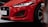 Close-up of the front of a red Jaguar F-Type car, featuring details of the headlight, grille, and sporty exterior design.
