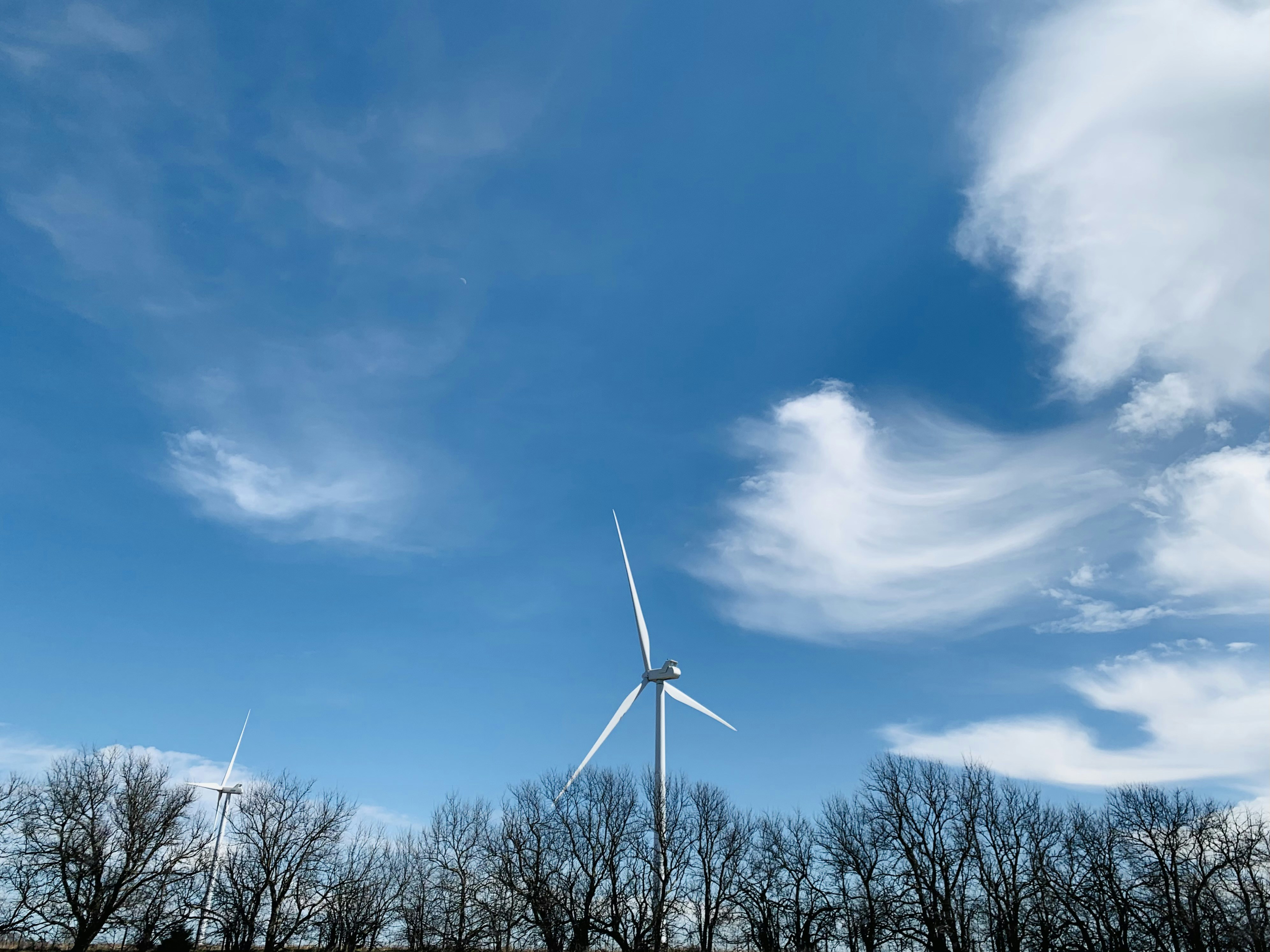 Éolienne blanche sous ciel bleu et nuages blancs pendant la journée