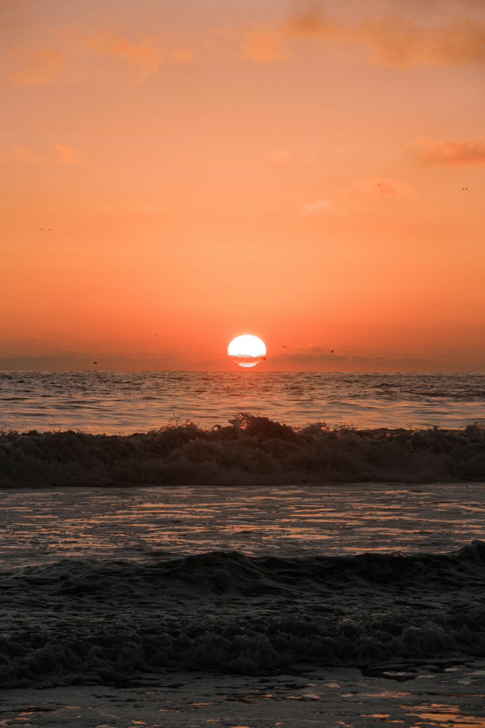 ocean waves crashing on shore during sunset