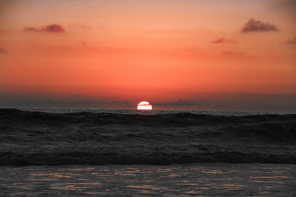 ocean waves crashing on shore during sunset