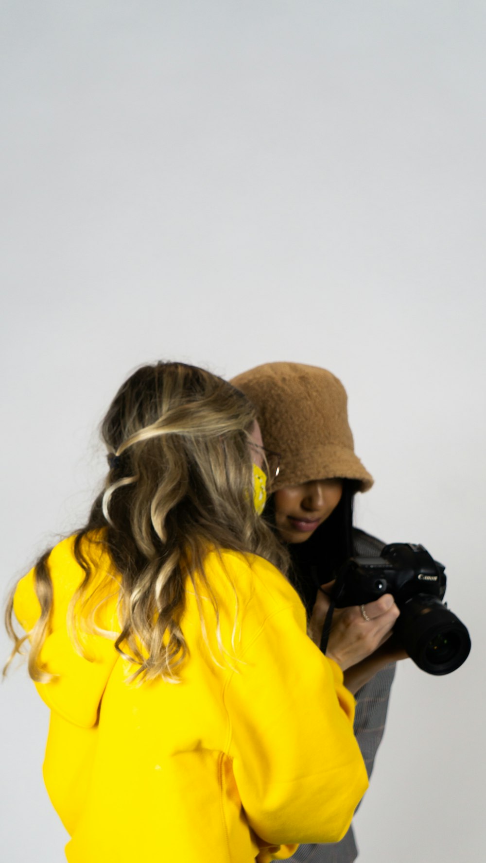 woman in yellow hoodie holding black dslr camera