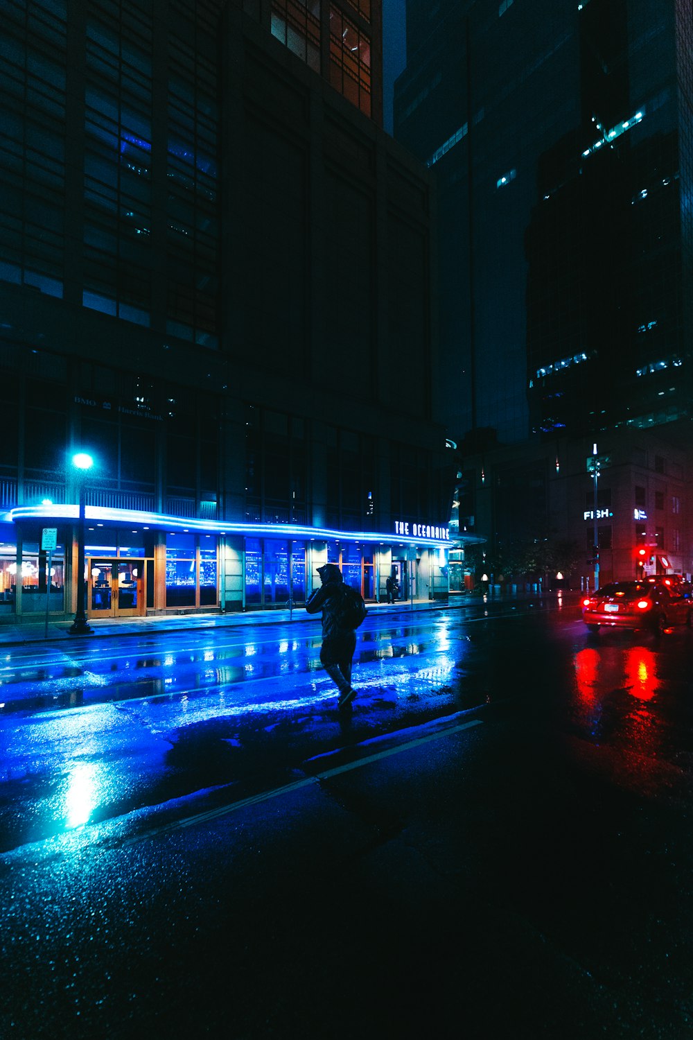 uomo in giacca nera che cammina sulla strada durante la notte