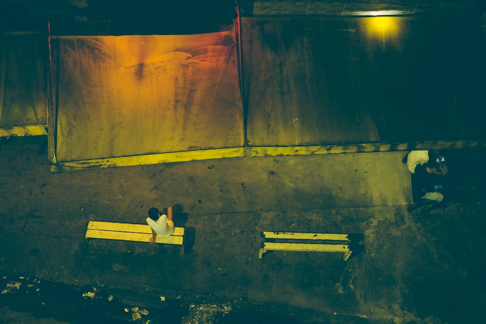 man in white shirt and black pants lying on wooden bench