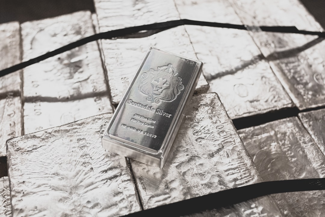 brown and white labeled box, A Scottsdale Mint stacker bar sits on top of a pallet of raw silver.