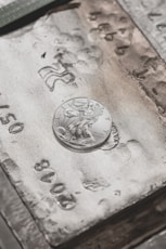 silver round coin on brown wooden table
