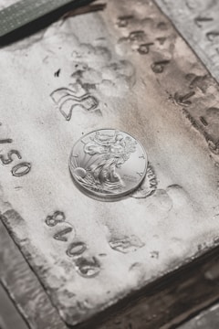 silver round coin on brown wooden table