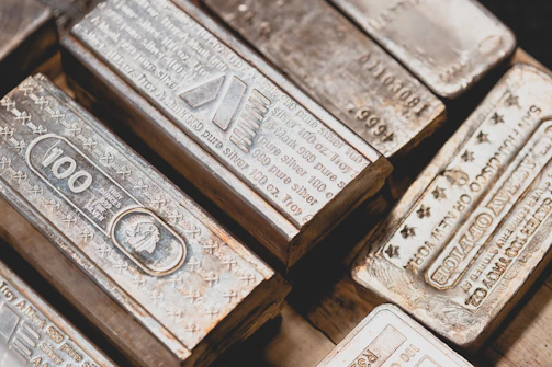Silver bullion bars reflecting soft light, arranged on a dark surface highlighting their purity.