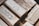A collection of silver bullion bars, intricately engraved with various inscriptions, stamps, and symbols, stacked closely together. The bars have a reflective surface and display a rich metallic texture.
