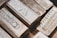 A collection of silver bullion bars, intricately engraved with various inscriptions, stamps, and symbols, stacked closely together. The bars have a reflective surface and display a rich metallic texture.