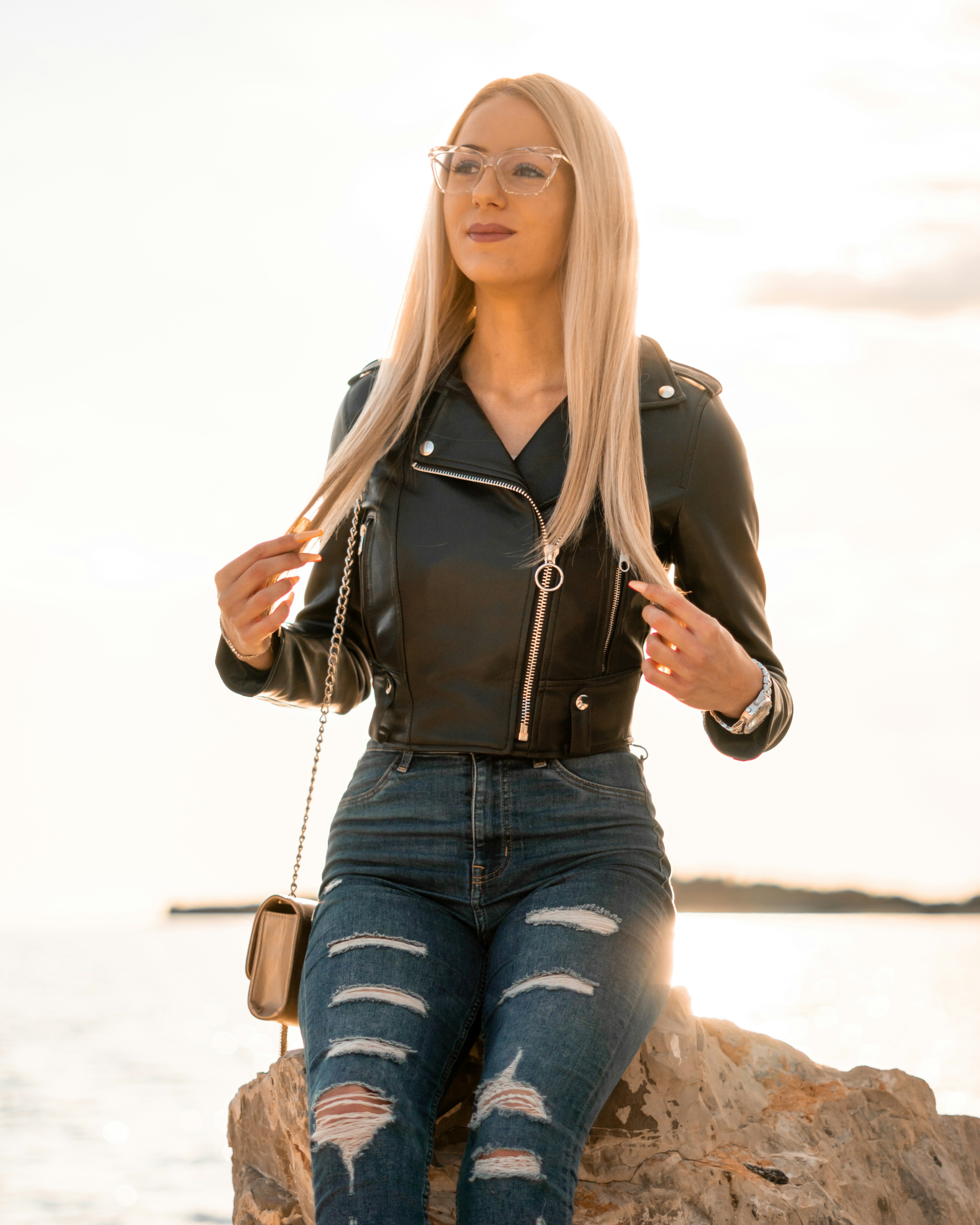 Woman in black leather jacket and blue denim jeans sitting on ground ...