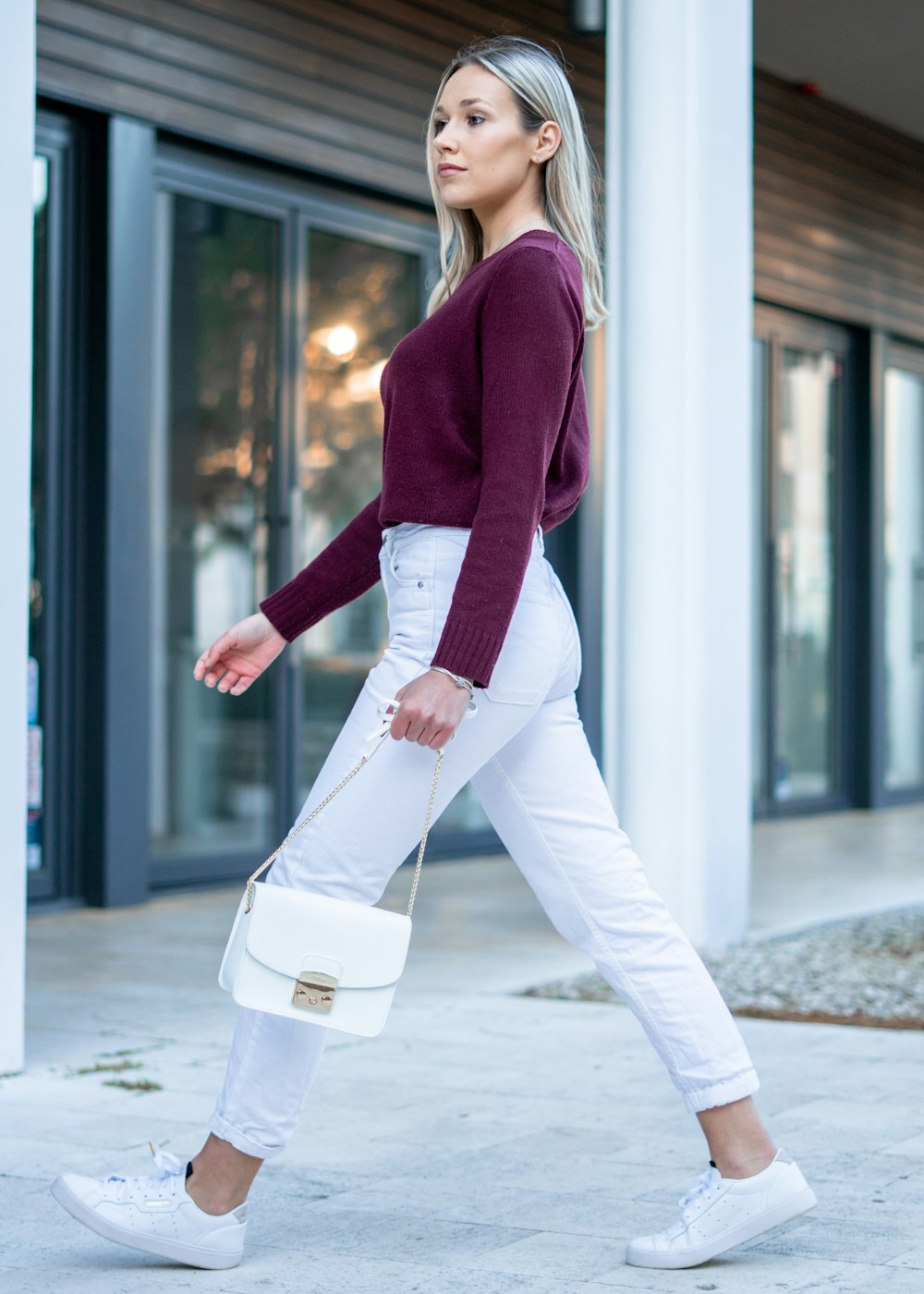 woman in red sweater and white pants walking on sidewalk during daytime