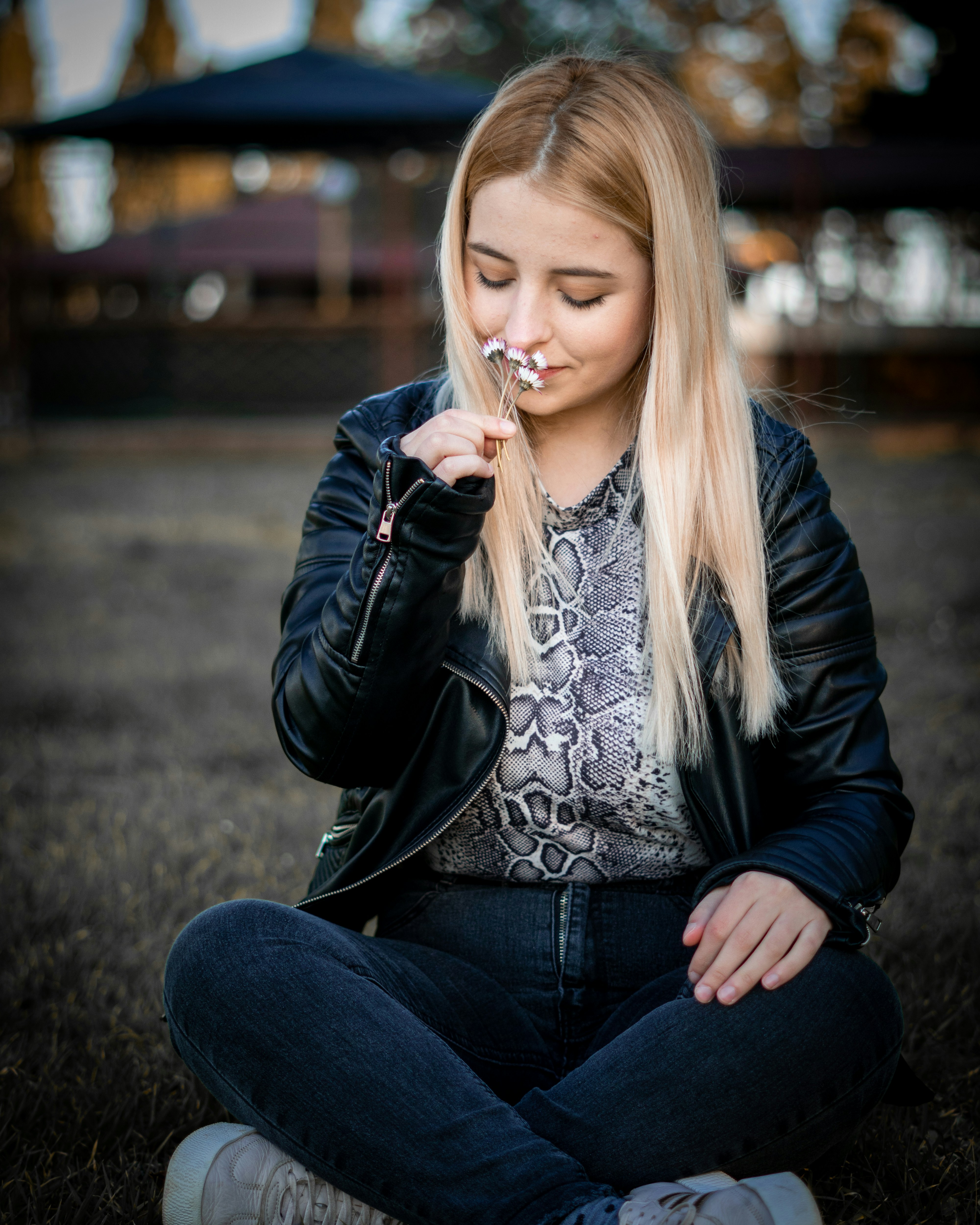 Woman in black leather jacket and blue denim jeans sitting on ground ...