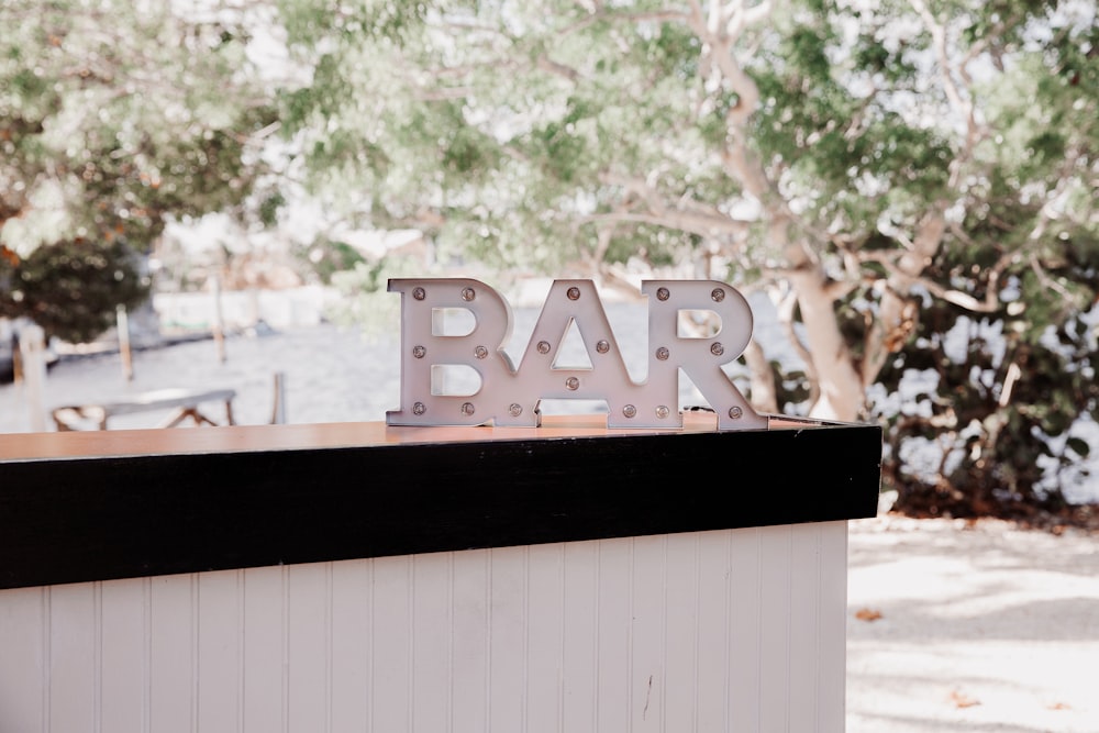 a metal bar sign sitting on top of a white building