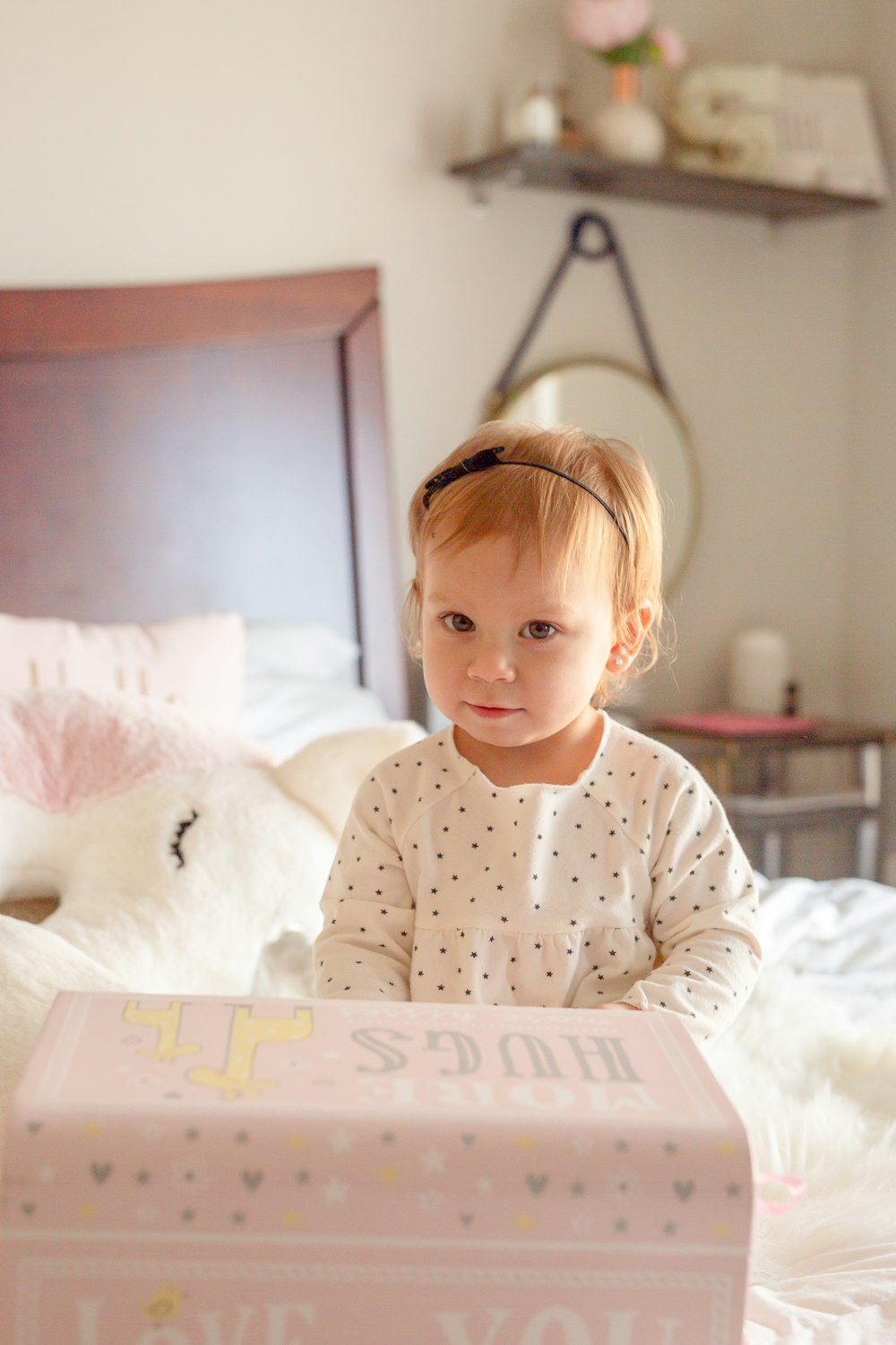 a little girl sitting on a bed holding a box