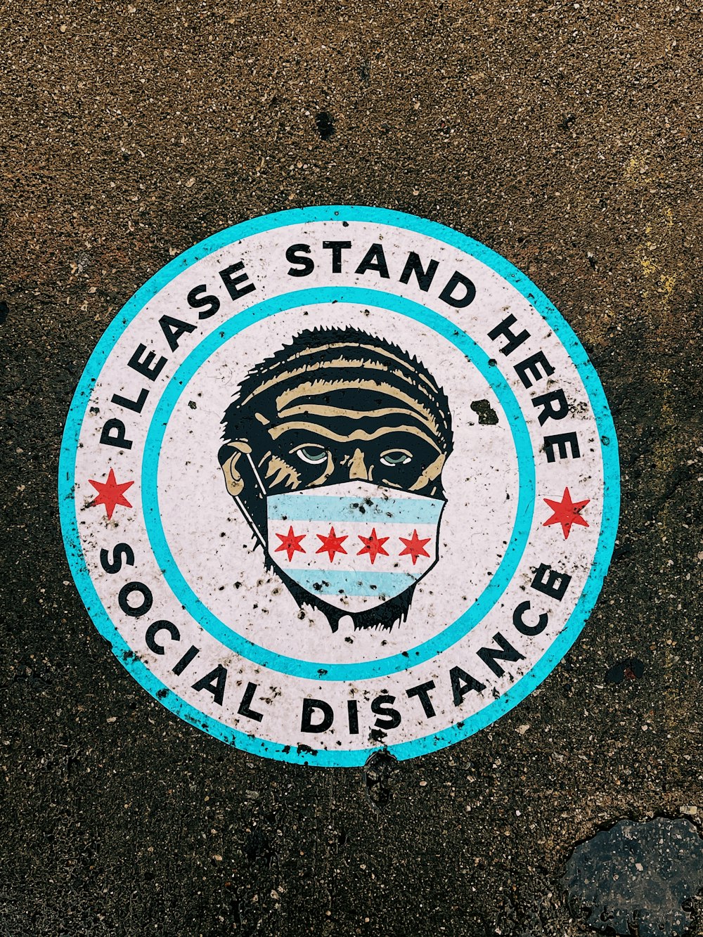 a blue and white sign that says please stand here social distance
