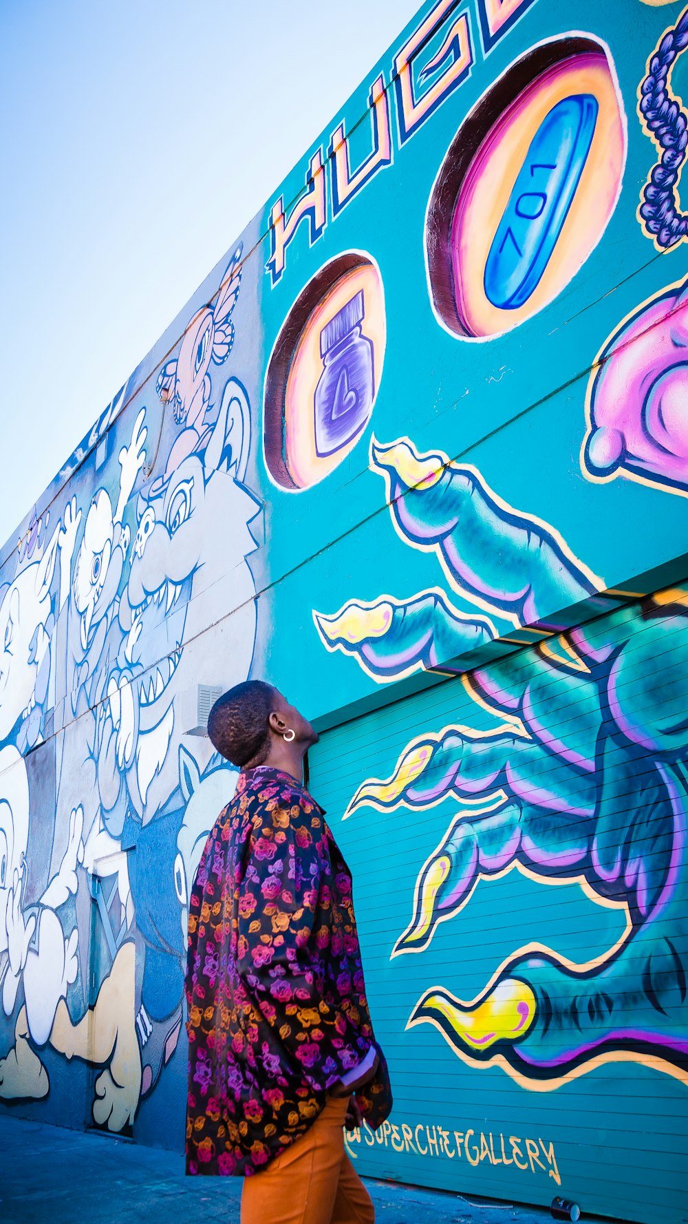 a man walking down a sidewalk next to a wall covered in graffiti