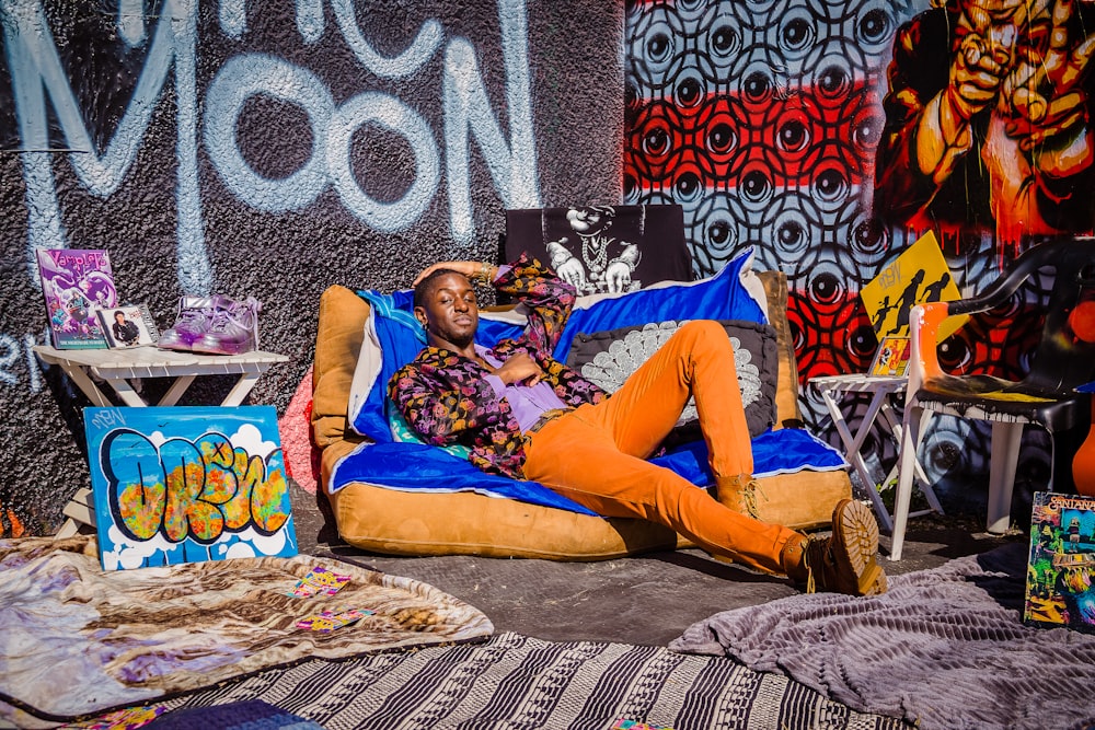 a man laying on a bean bag chair in front of a wall covered in graffiti