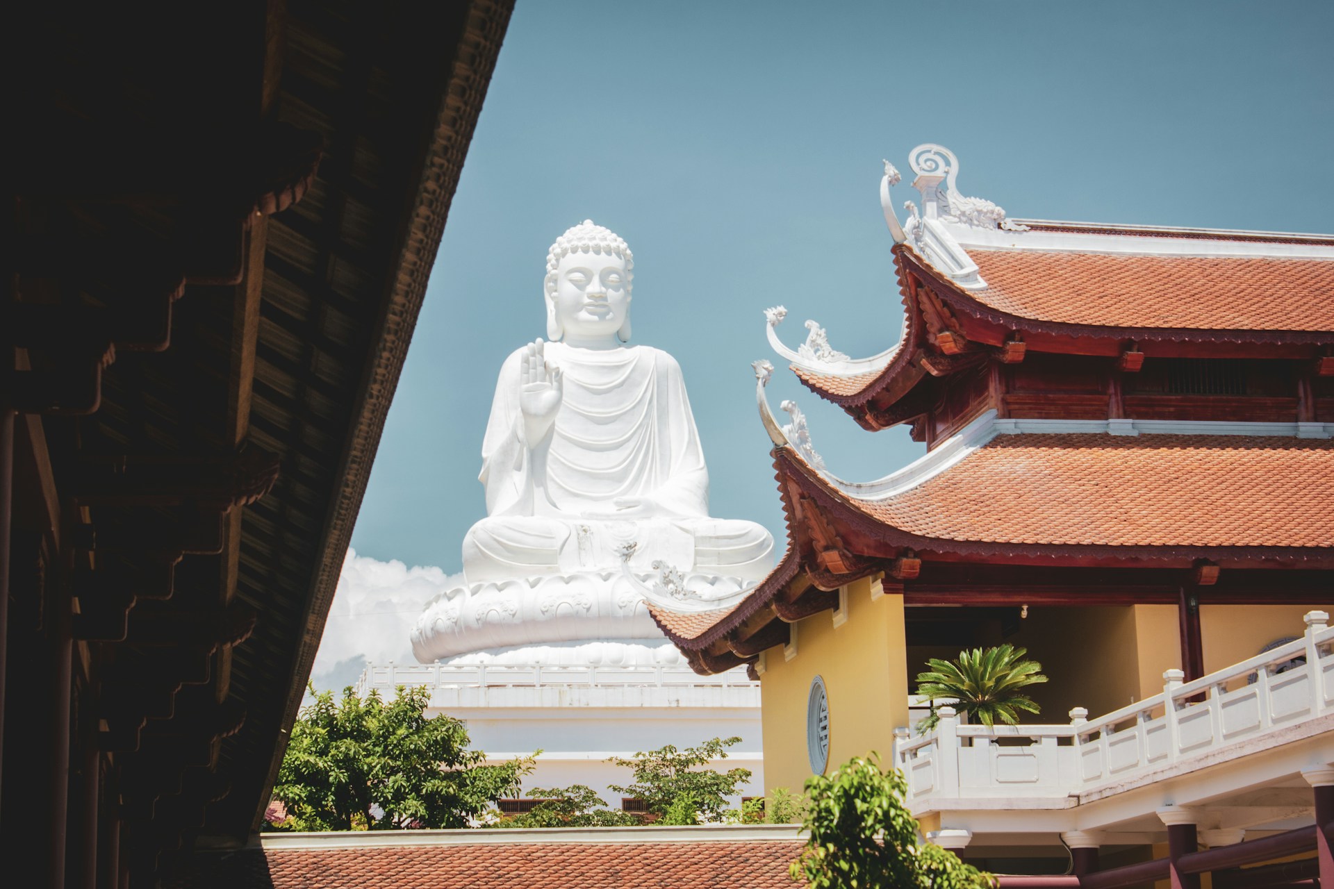 a large white buddha statue sitting in front of a building