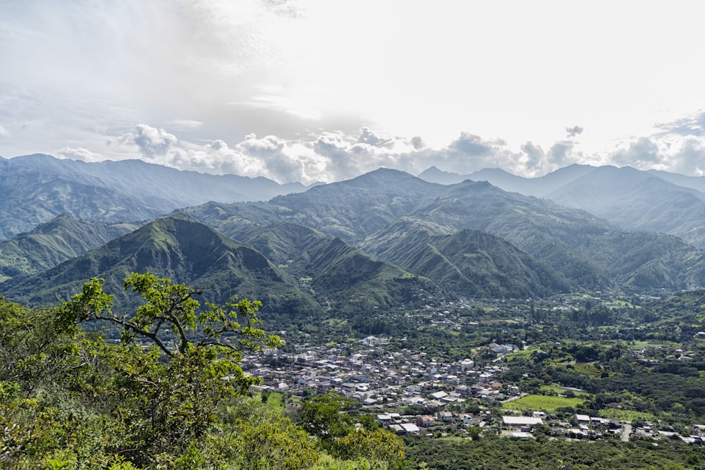 houses on green grass field near mountains under white clouds during daytime