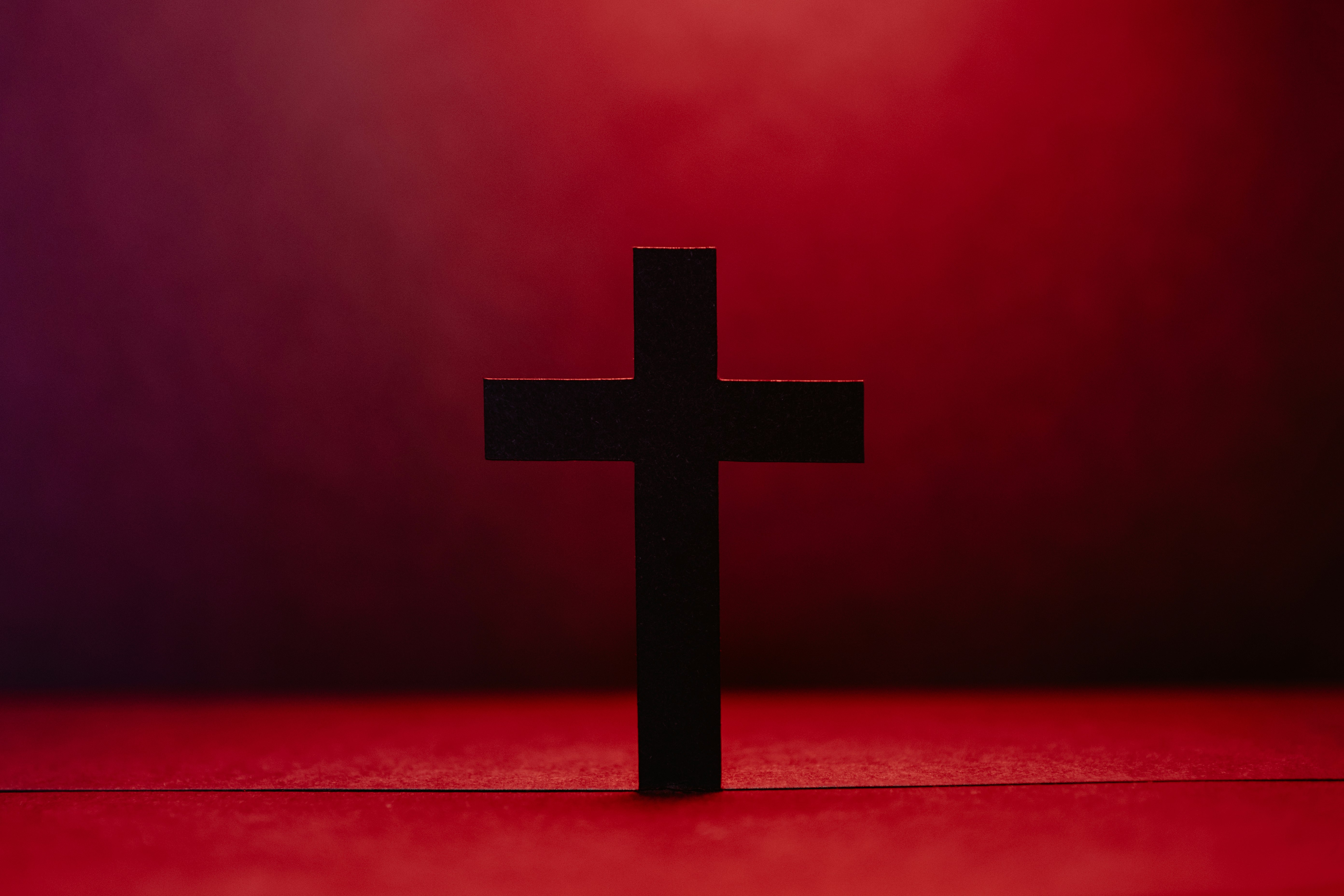 Paper cut cross with red light behind it