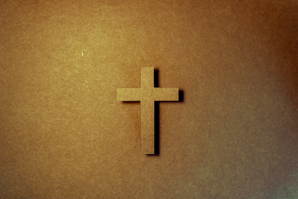 Close-up of a hand-painted Christian symbol on textured canvas with warm lighting.