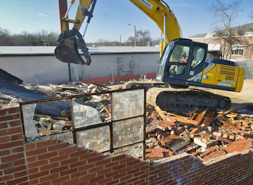 yellow and black excavator on brown brick wall during daytime