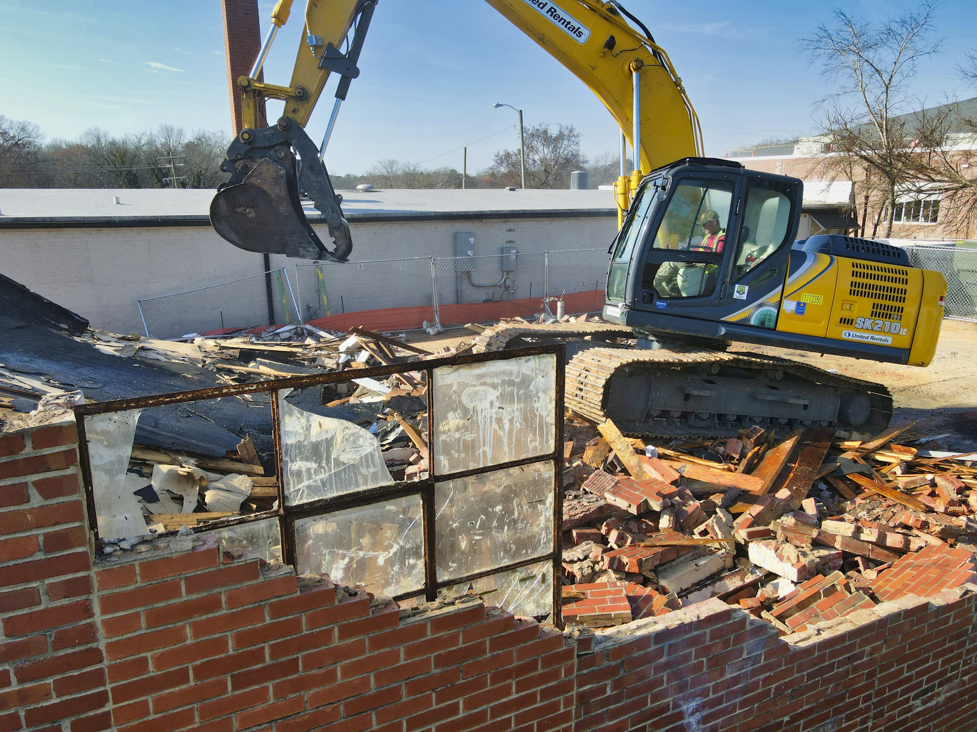 Excavator attachment removing a brick wall section