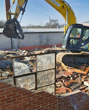 yellow and black excavator on brown brick wall during daytime