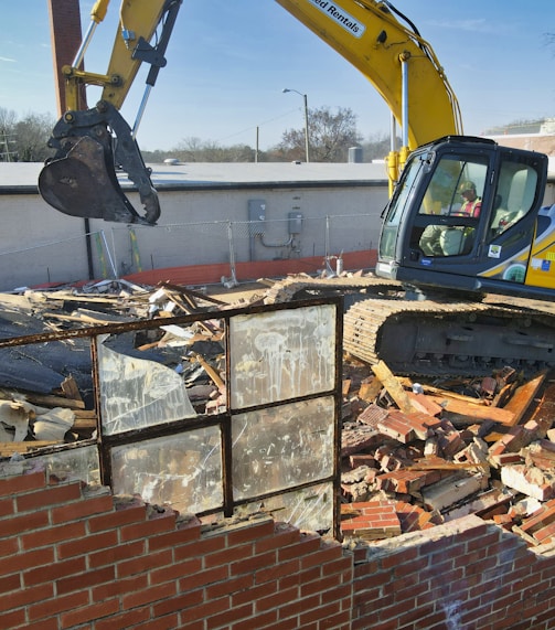 yellow and black excavator on brown brick wall during daytime