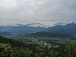 A panoramic view of a serene Himalayan valley with a winding river and scattered villages.