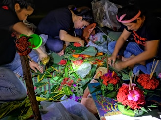 A group of smiling community members crafting colorful decorations at a sunny table.