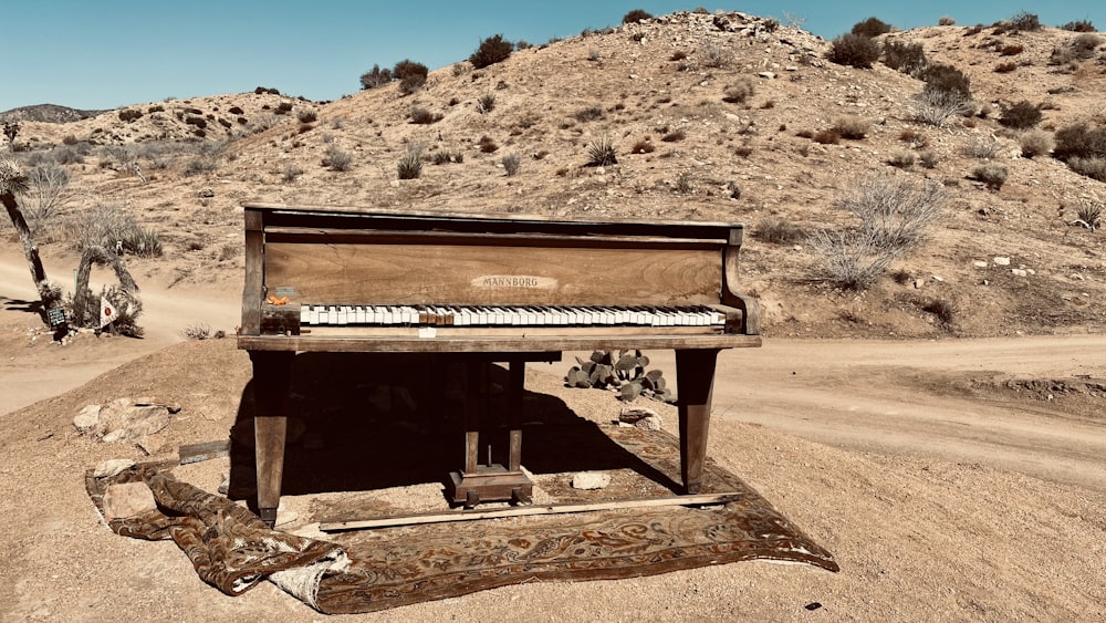 brown wooden upright piano on brown sand during daytime