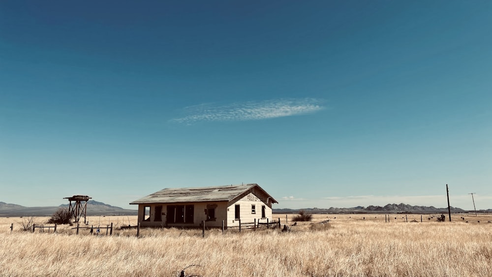 white and brown house on brown grass field under blue sky during daytime