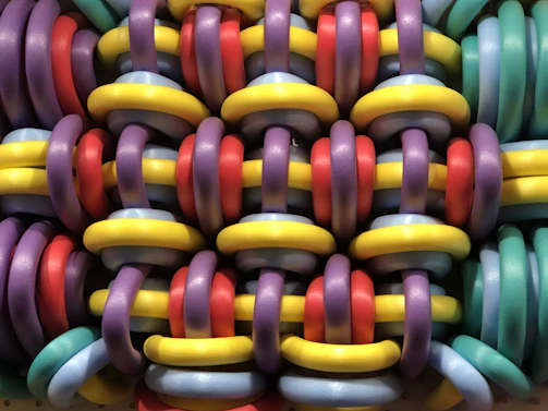 Close-up of colorful twirléa hoops stacked together on a wooden floor.