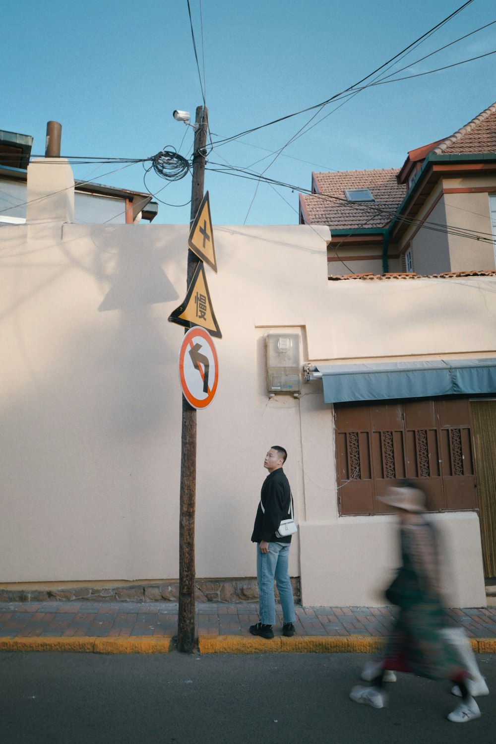 man in black jacket standing near white wall